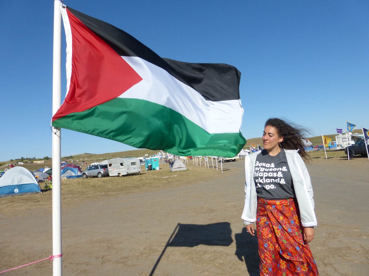 The author standing by the Palestinian flag in Oceti Sakowin Camp.